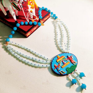 Front View of Pallaki Splendor necklace by Bujjis with hand-painted pallaki motif on wooden base, strung with blue and white beads.
