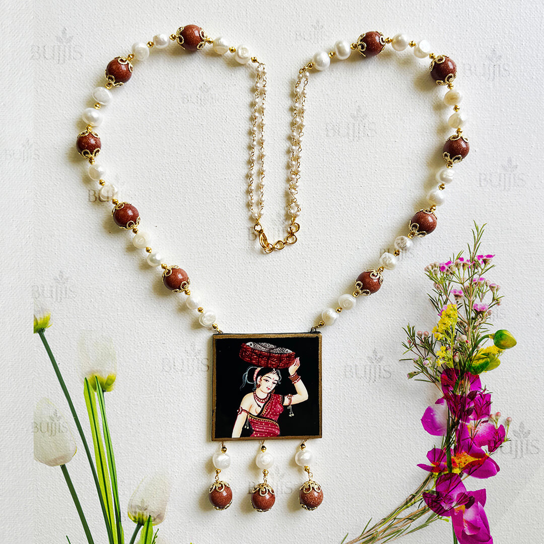Front View of Rustic Elegance necklace by Bujjis featuring hand-painted Nirmal art of a rural woman carrying a basket, accented with pearls and gold beads.