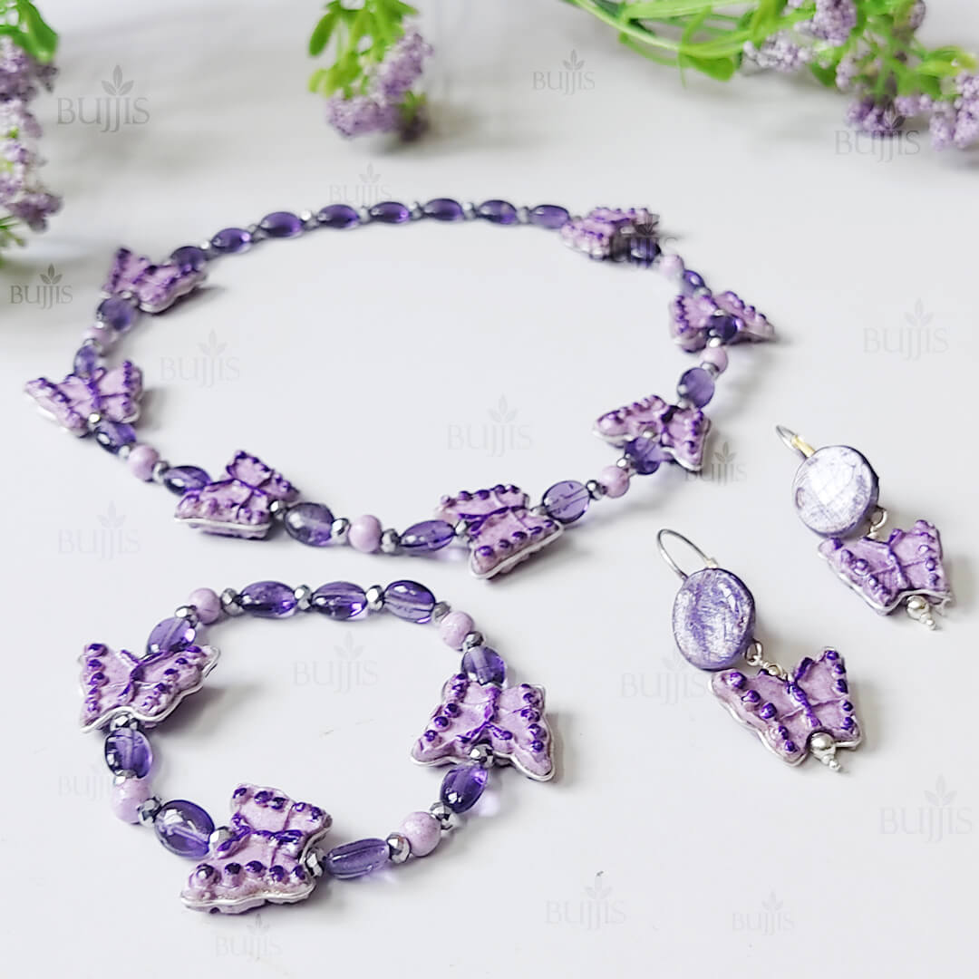 purple kids jewellery set with butterfly charms including necklace, bracelet, and earrings handmade from polymer clay