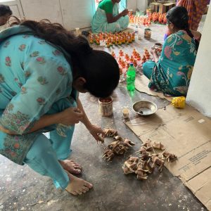 A Bujjis team member carefully inspecting or touching a piece of wearable Indian art jewellery at the artisan's workshop."
